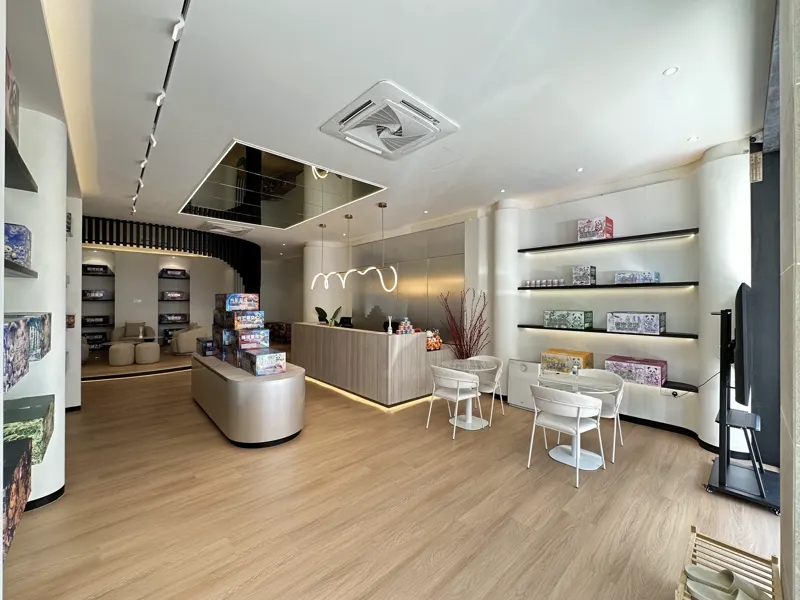 The main showroom floor looking towards the service counter, with a central display plinth and lit shelving down both walls.
