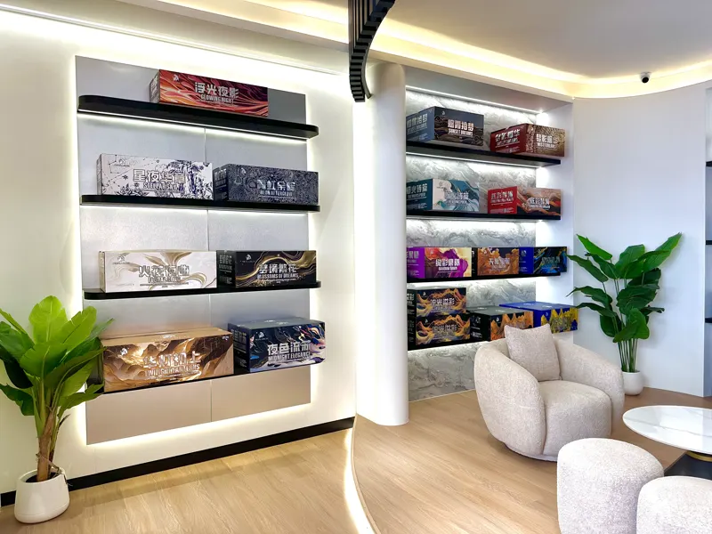The premium wall: larger boxed shells on lit shelves in a recessed alcove, beside a boucle armchair and a potted plant.
